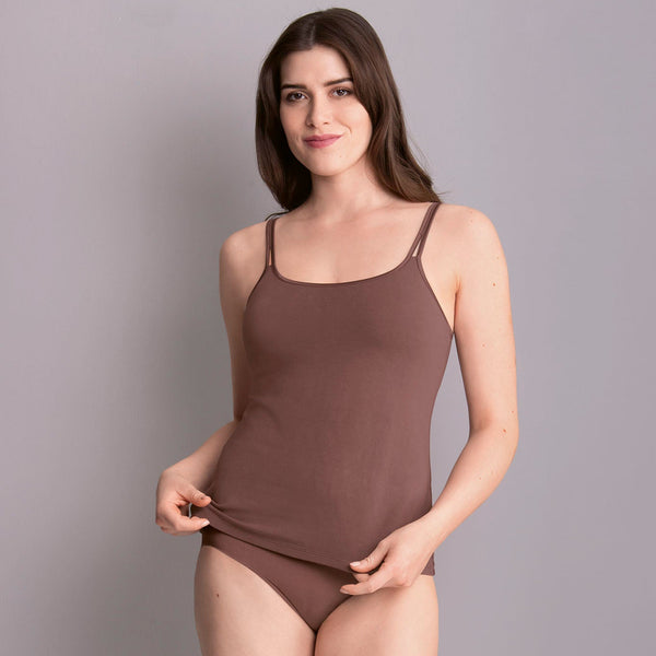 A woman wearing a beige camisole top with adjustable straps and a round neckline