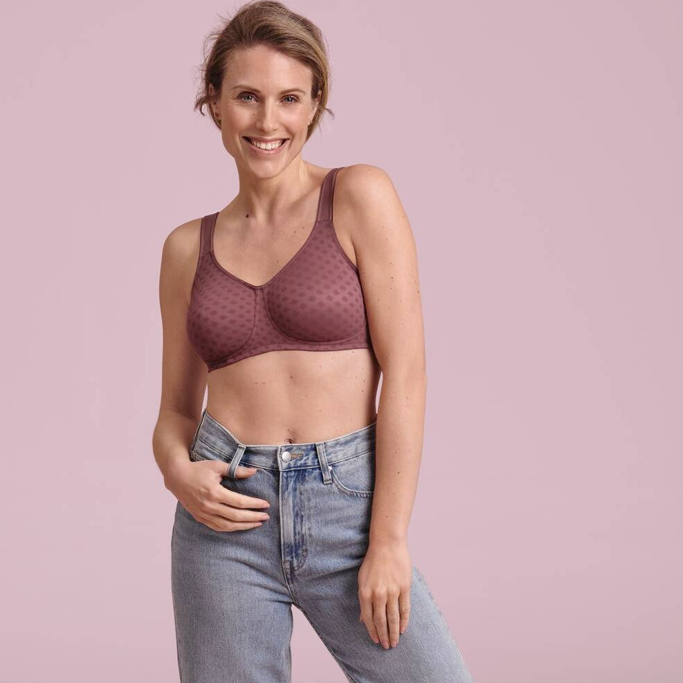 Woman wearing a bra and jeans on a pink background