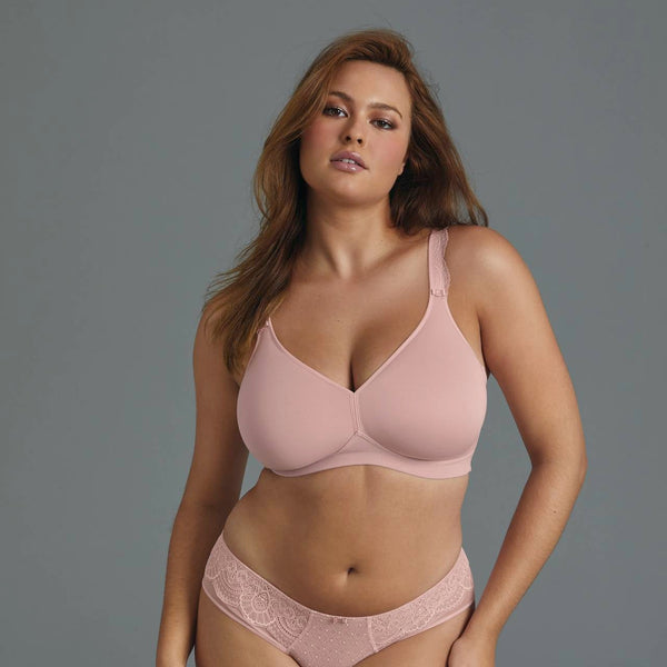 Woman wearing a pink bra and panties set against a gray background