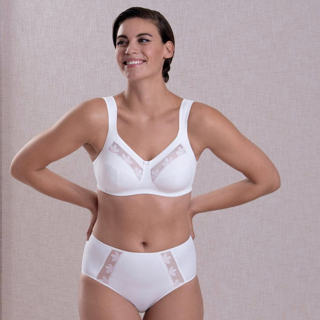 Woman wearing a white bra and underwear set against a neutral background